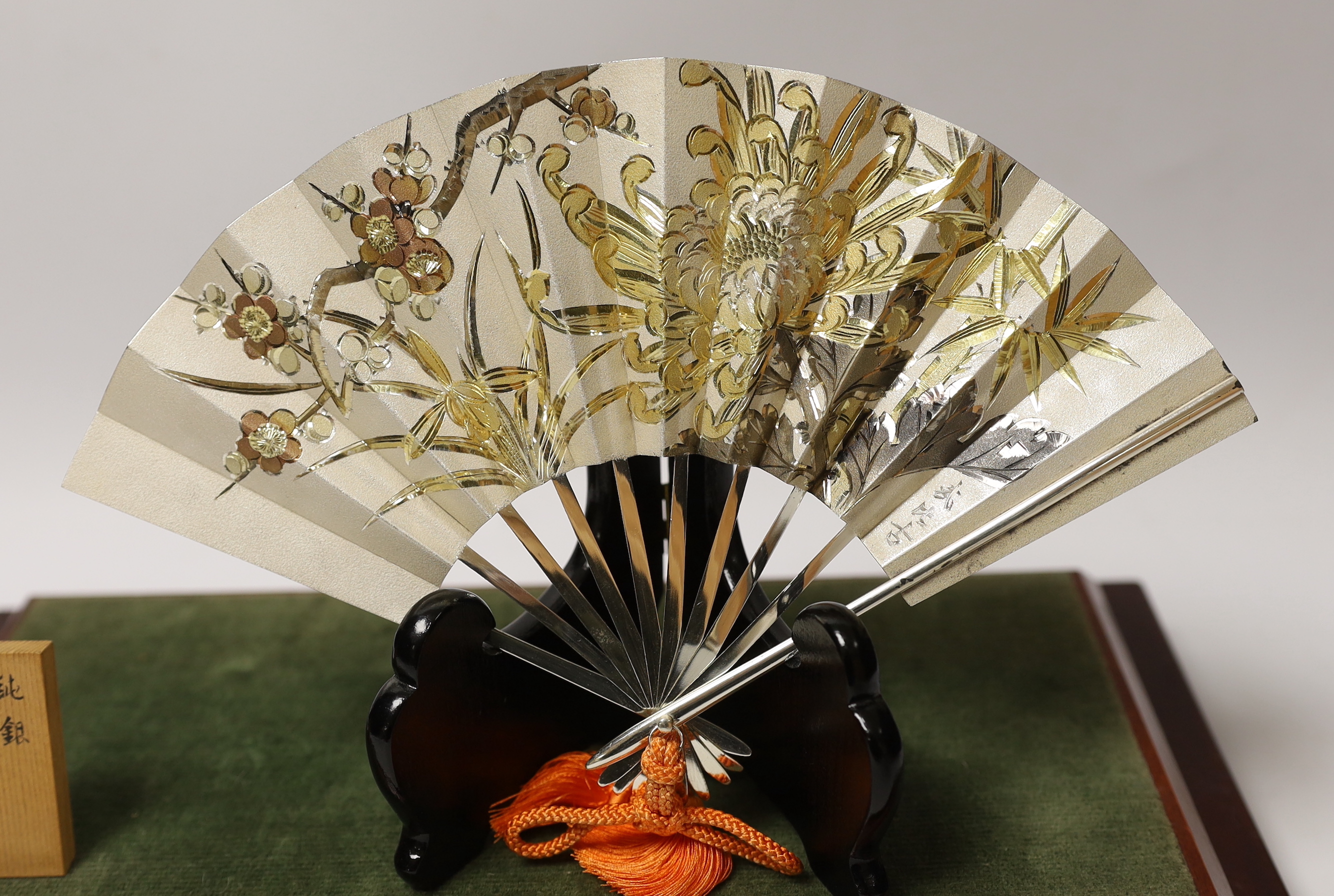 A Japanese white metal fan ornament on stand, signed, 24cm wide